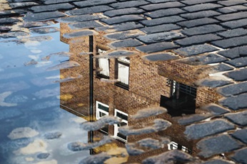 Cobblestone house reflection in a puddle