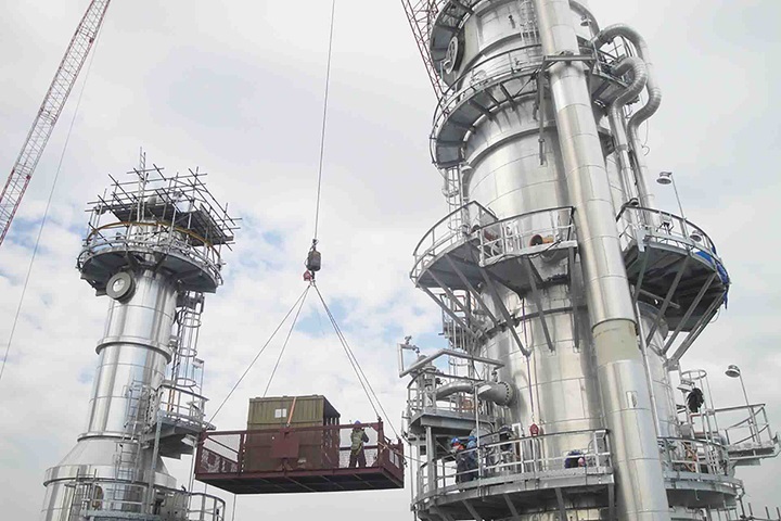 Sulzer employee lifted up in a secure box with a crane between two towers