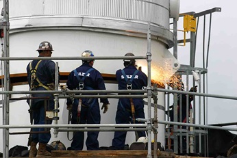 Three employees on a column platform welding