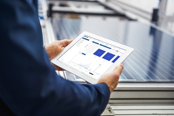 Businessman in solar factory holding tablet with bluebox screenshot