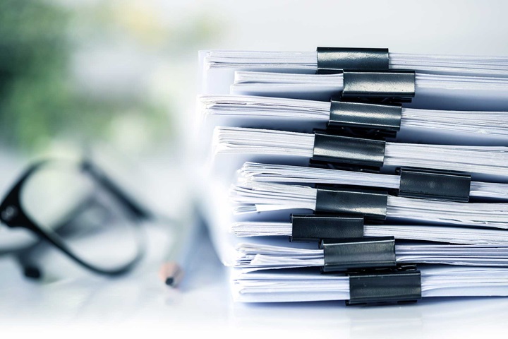 A pile of files with a pencil and glasses