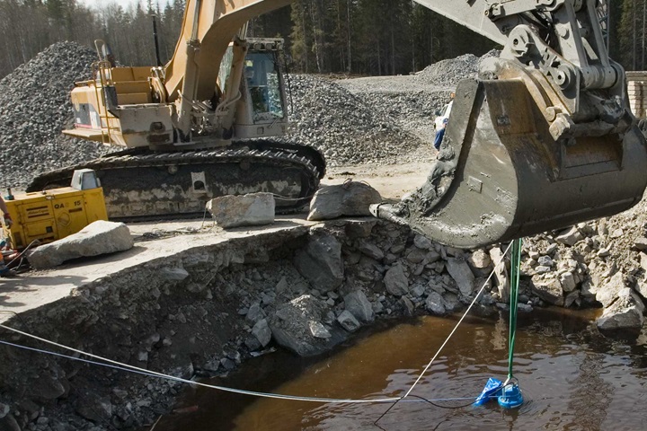 Excavator holding drainage pump in pit at site for dewatering in construction