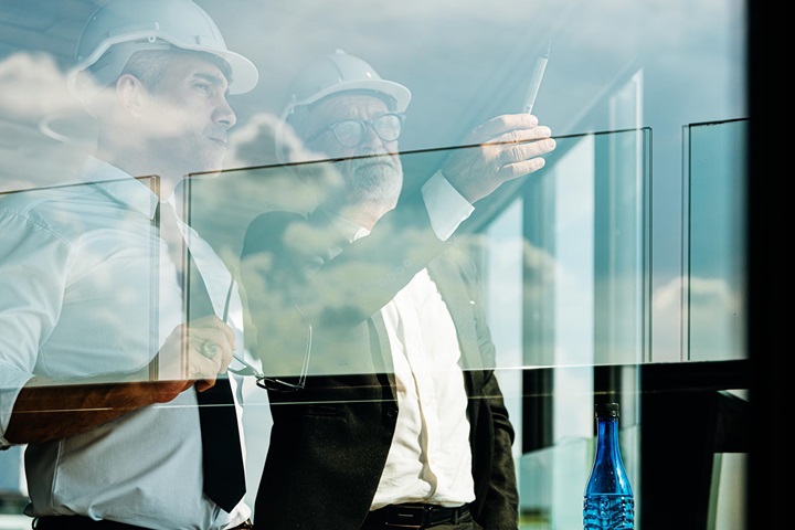 Two workers with helmets looking outside a window